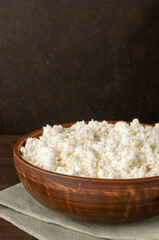 Cottage curd cheese in a wooden bowl grey table background