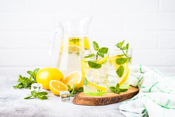 Lemonade in two glasses at white table. Summer drink, traditional refreshment cocktail.