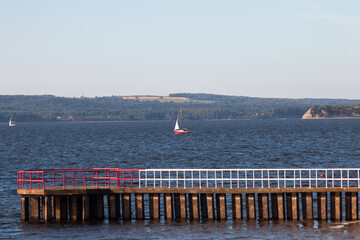 view of a red yacht on the river behind a concrete pier