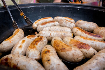 Fried juicy delicious pork sausages. View from above. Dark metal background, frying pan