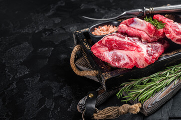 Raw Organic Beef Short Ribs Ready to Cook in wooden tray with herbs. Black background. Top view. Copy space