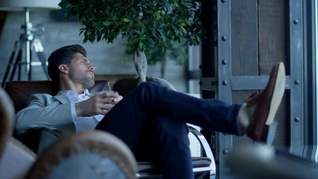Rich man enjoying vacation life cognac in luxury interior. Businessman relaxing