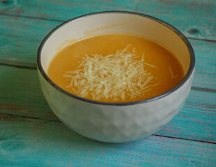 a plate of vegetable soup with mashed potatoes, carrots, onions, parsley root on a brown wooden table is decorated with grated cheese. restaurant. gluten-free.