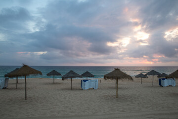 End of summer. closed parasol and stowed chairs on an empty beach. End of the beach day.