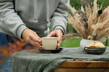 Autumn mood. Female hands pouring tea in mug, drinking tea outdoors.