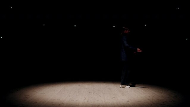 empty theatre scene with soffit light and walking strange girl in darkness, unusual dance performance