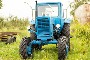 Obraz premium blue old tractor on orchard, simple mechanical technology agricultural vehicle. Nobody. Horizontal 