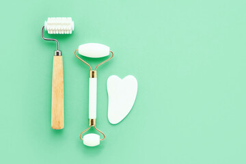 Massage rollers and gua sha massager for the face on green background. Selfcare, skincare concept