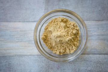 Bowl of grated ginger on gray wooden background, top view