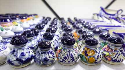 Fototapeta na wymiar bunch of salt shakers, souvenirs for tourists in Puebla, Mexico, colorful salt shaker of traditional mexican talavera pottery repetitive pattern texture background