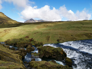 Rocks in the river to the waterfall Sk&oacute;gafoss in iceland walkinga and hiking with idyllic blue sky on a road 