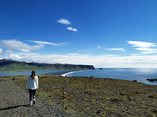 Couple vacation girlfriend walking along the shore in iceland black beach in iceland with the sea