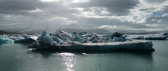 Sun is shining and reflecting on iceberg in iceland water blue sea glacier cold stop break roadtrip vacation