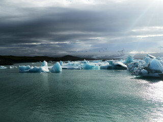 Sun breaks through shining on some ice iceberg glacier in iceland sea on a roadtrip vacation