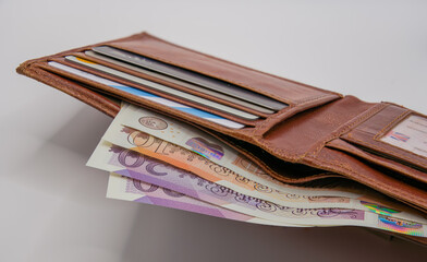 a light brown leather wallet with bank cards and a detailed close-up of new plastic note currency