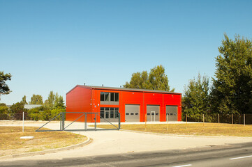 Obraz premium a straight-walled hangar, in the photo a production hangar against the background of trees and blue sky, a fence in the foreground