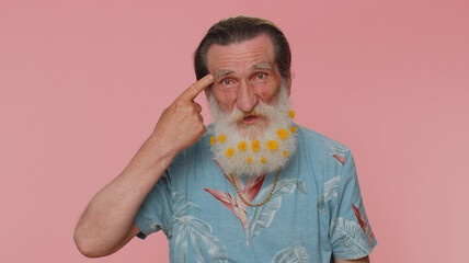 You are crazy, out of mind. Senior man with flowers in beard pointing at camera and showing stupid...