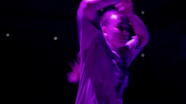 teenage girl dancing hip hop in dance battle in purple light, street dance and subculture of teens