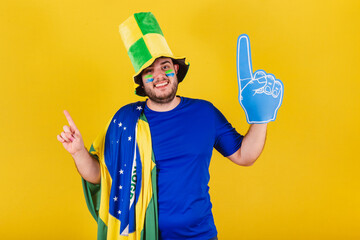 brazilian caucasian man, soccer fan from brazil, wearing hat and foam finger, dancing, doing...