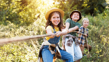 group of cheerful children tug of war in the summer outdoors