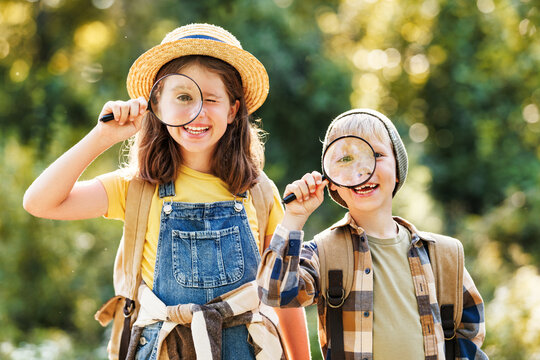 cheerful happy kids with  magnifying glass  studies the environment in summer in nature