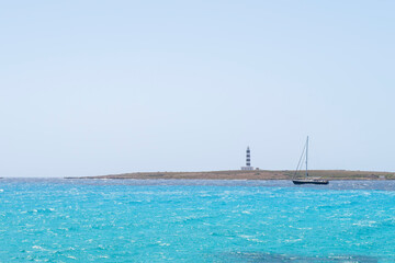 a sailboat skirts a cape with a blue and white lighthouse, on a sea of turquoise waters, clear sky,...