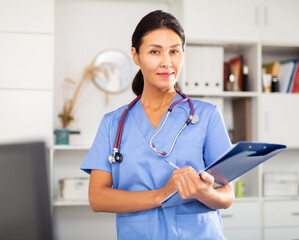 Positive woman asian doctor is standing with documents in clinic