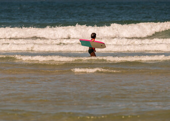 boy with orange equipment and bodyboard practices in the waves of Aveiro beach