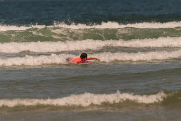 boy with orange equipment and bodyboard practices in the waves of Aveiro beach