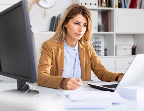 Office manager works with documents and laptop in office