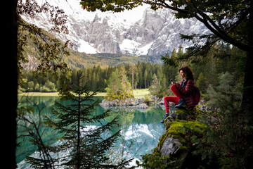 Woman Backpack Tourist Sitting Near An Alpine Lake Using Mobile Phone
