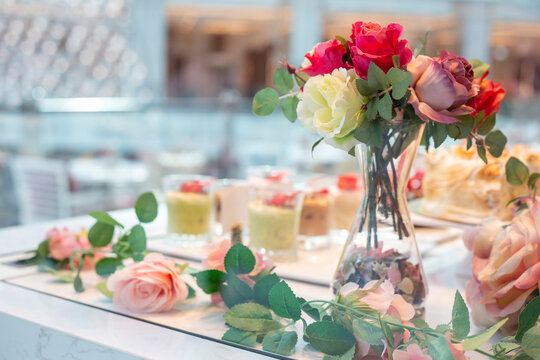 Wedding table with desserts decorated with artificial roses. Festive table with floral decor