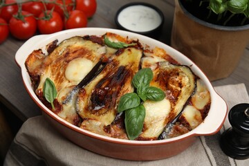 Delicious eggplant lasagna in baking dish on wooden table