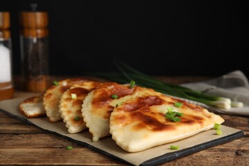 Board with delicious fried chebureki on wooden table