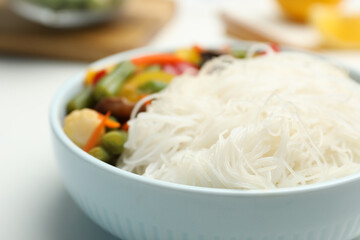 Tasty cooked rice noodles with vegetables on table, closeup