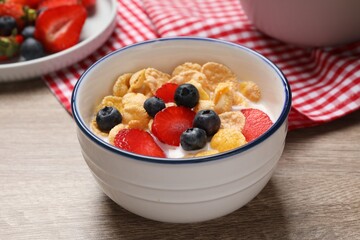 Delicious crispy cornflakes with milk and fresh berries on wooden table, closeup