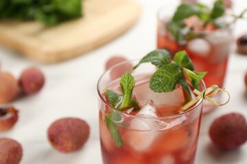 Lychee cocktail with mint and ice on white table, closeup