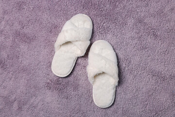 Fototapeta na wymiar Soft white slippers on fluffy grey carpet, top view