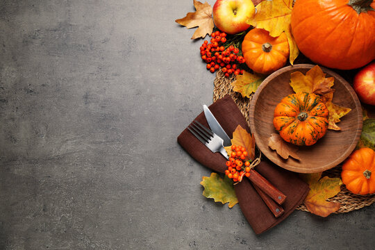 Flat lay composition with tableware, autumn leaves and vegetables on grey background, space for text. Thanksgiving Day