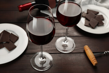 Tasty red wine and chocolate on wooden table