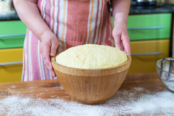 hostess prepares the dough. Dough that has doubled in size, dough that has risen, proofed dough in a wooden bowl