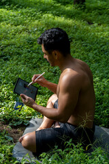 young man explaining drawing on his ipad tablet, while teaching chakra, yoga and meditation class,...