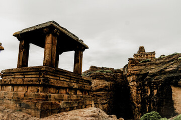 The remnants of pavilions (open mandapas)at Badami, perhaps once part of a Chalukya palace, are balanced on cliffs with temples in the distance, Karnataka,India