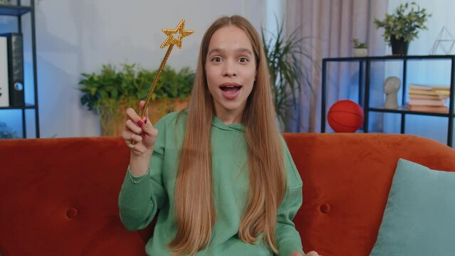 Portrait of student girl child kid magician wizard gesturing with magic wand fairy stick, making wish come true, casting magician spell, advertising holidays sale discount. Young woman at home room