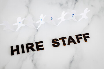 Hire Staff text with paper people chain and question marks on vacant positions to fill, staff...