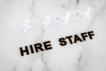 Hire Staff text with paper people chain and question marks on vacant positions to fill, staff...
