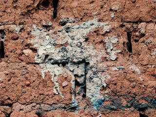 White paint on antique adobe clay wall surface. Vintage mud structure with white paint stain. 