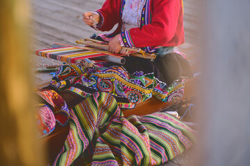 Indigenous woman showing traditional weaving technique and textile making in the Andes mountain...