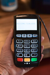 Womans hand holding retail store payment terminal
