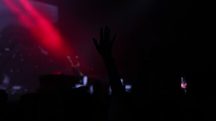 A slow motion shot of crowd rising their hands and listing the DJ music which is going on stage